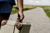 Refugee child goes on the road with her  suitcase