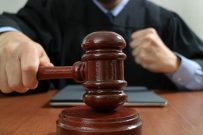 justice and law concept.Male judge in a courtroom with the gavel,working with smart phone,digital tablet computer docking keyboard,eyeglasses,on wood table,filter