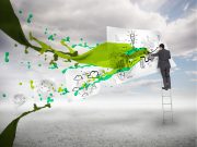 Businessman drawing on a paper next to green paint splash with blue sky on the background