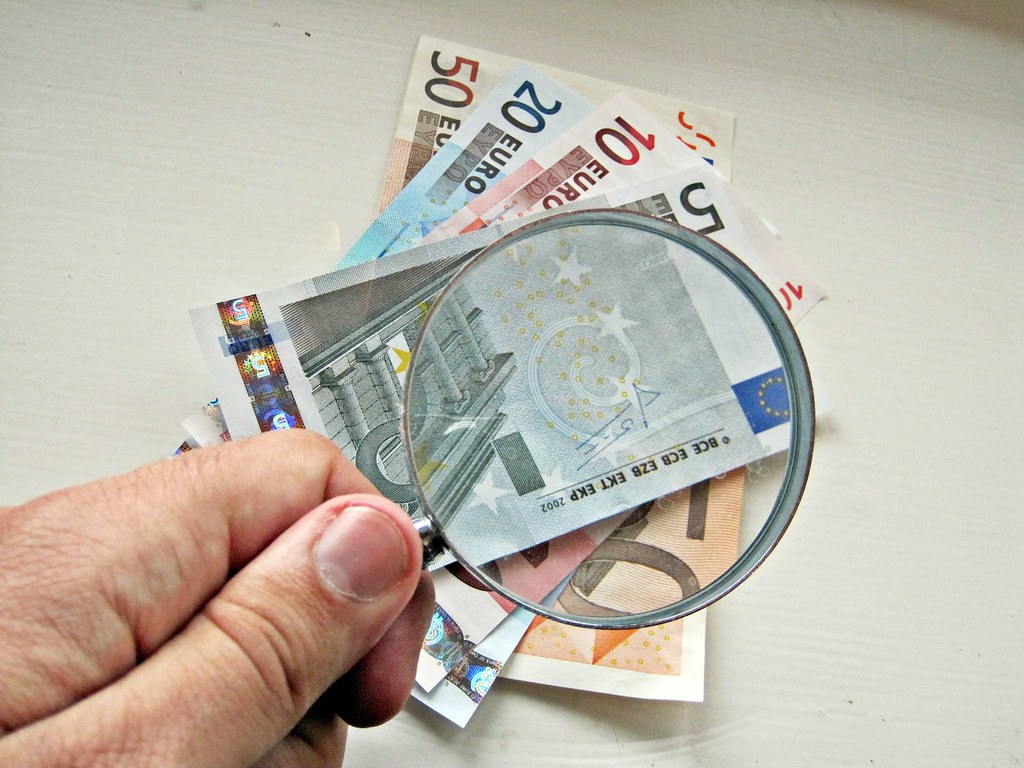A magnifying glass scrutinizing financial documents.